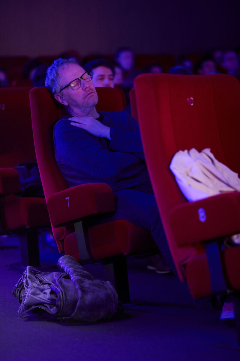 Mann sitzt mit geschlossenen Augen im Kinosessel